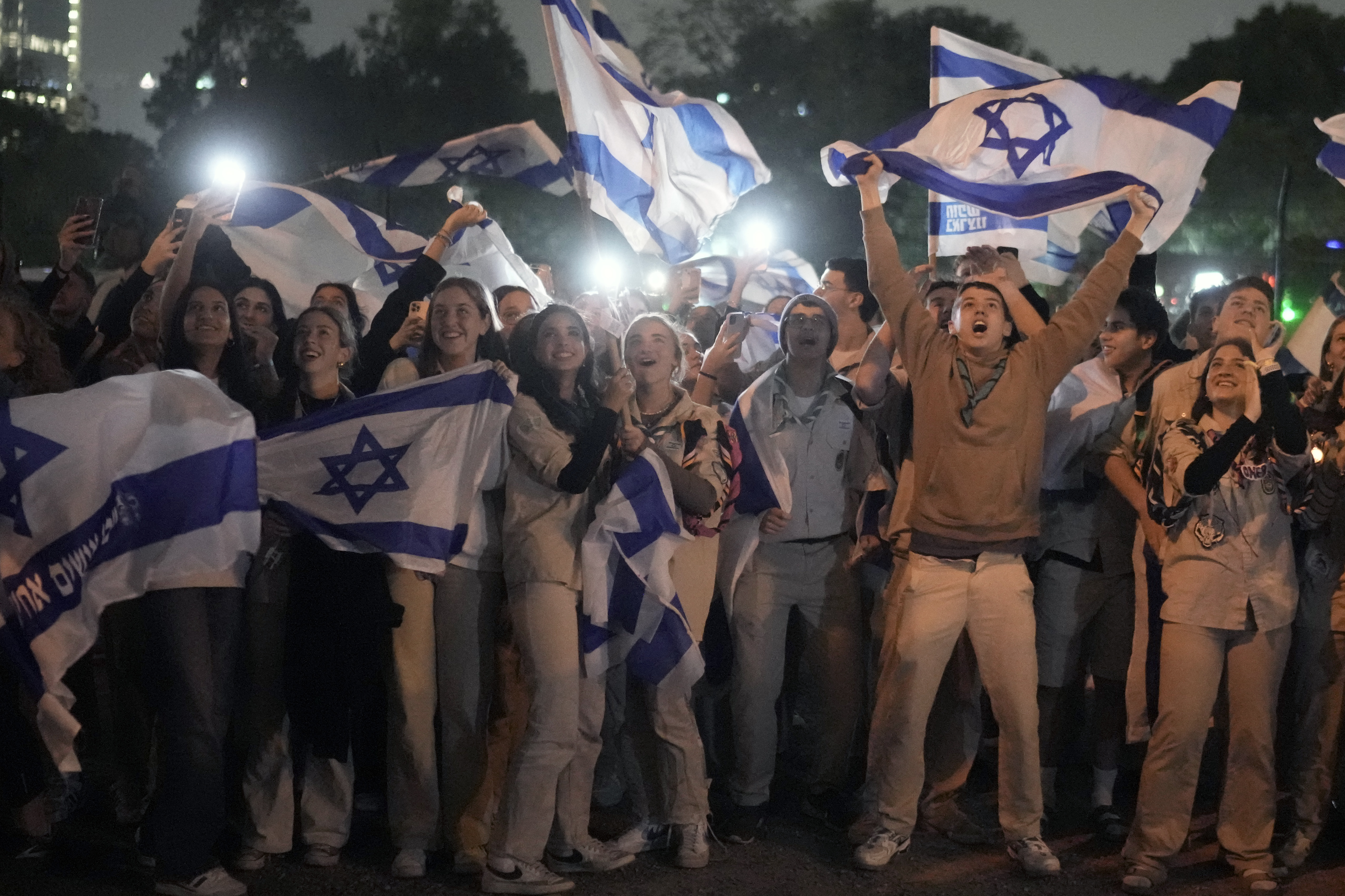 A group of Israelis celebrate as a helicopter carrying hostages released from the Gaza Strip lands at the helipad of the Schneider Children