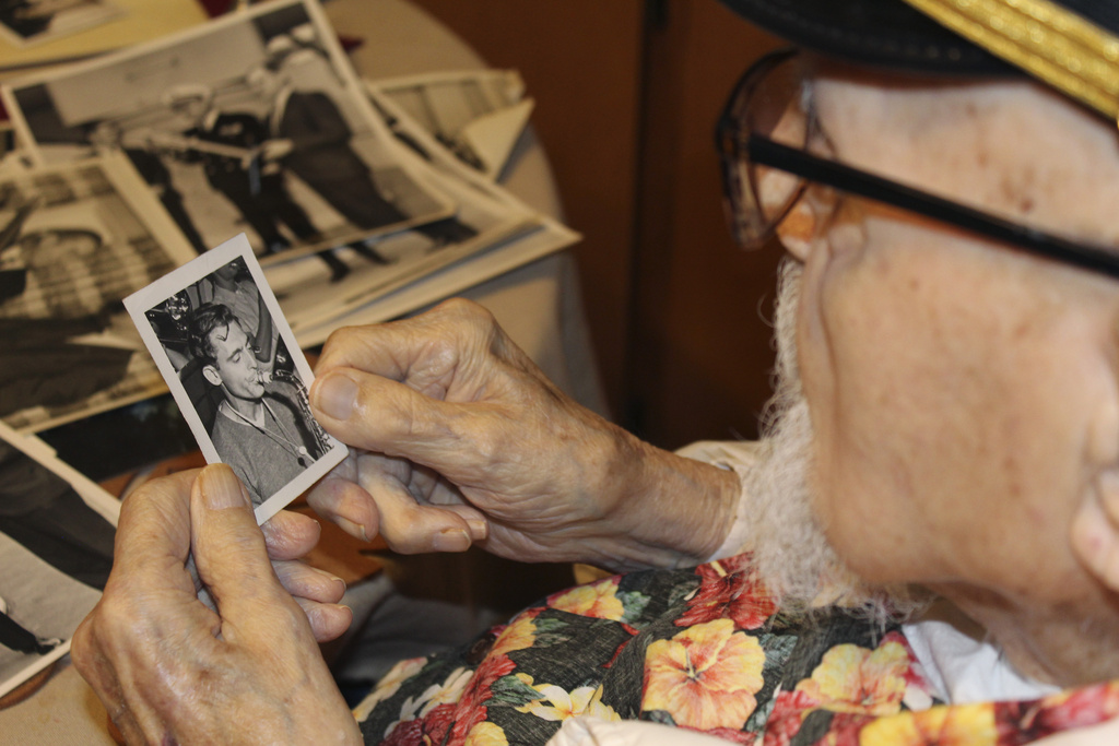 Pearl Harbor survivor Ira "Ike" Schab, 103, looks at an old photo of himself with a saxophone while sitting at the kitchen table in his home in Beaverton, Ore.