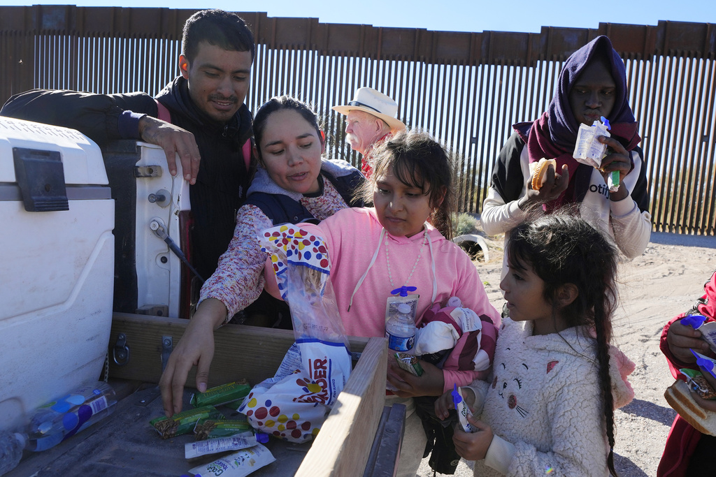 Gerston Miranda, left, and his family from Ecuador get food and water before joining hundreds of migrants gathering along the border