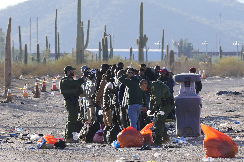 Members of the U.S. Border Patrol and U.S. Customs and Border Protection organize a group of migrants as hundreds of migrants gather along the border 