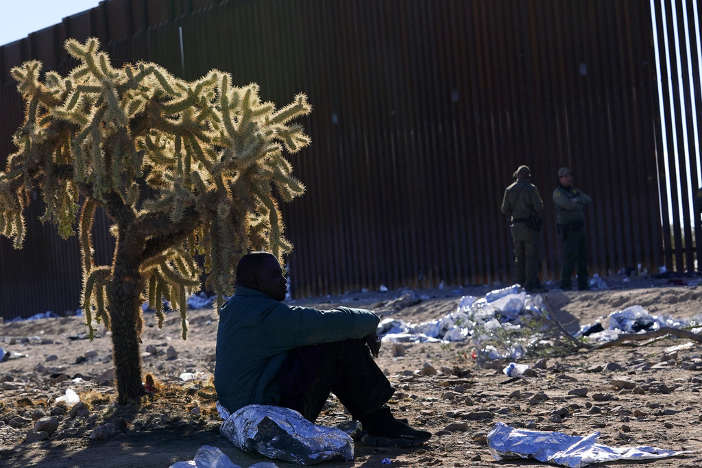 A migrant sits in the shade provided by a desert cholla cactus 