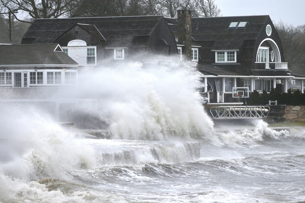 High winds drive surf into a retaining wall in front of a residence in Mattapoisett, Mass.