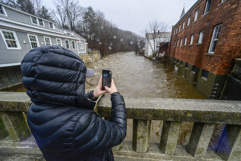 Cassidy Doolittle of Wilmington, Vt., takes a photo of the water marker on the side of a building in downtown Wilmington as the Deerfield River gets to 14 feet high