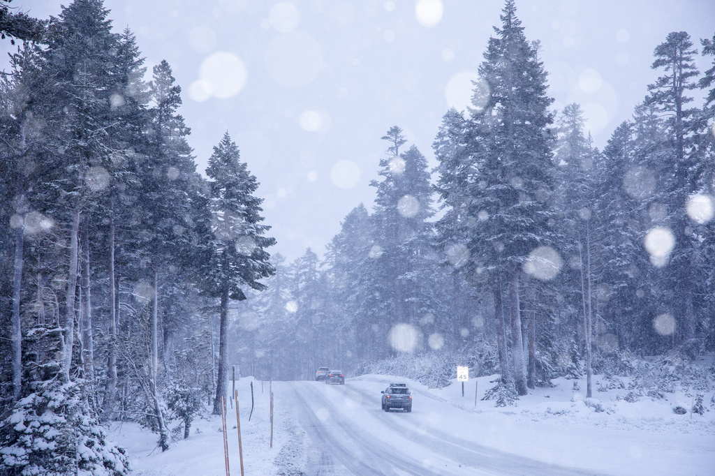 Cars make their way through the snow in Mammoth Lakes, Calif.