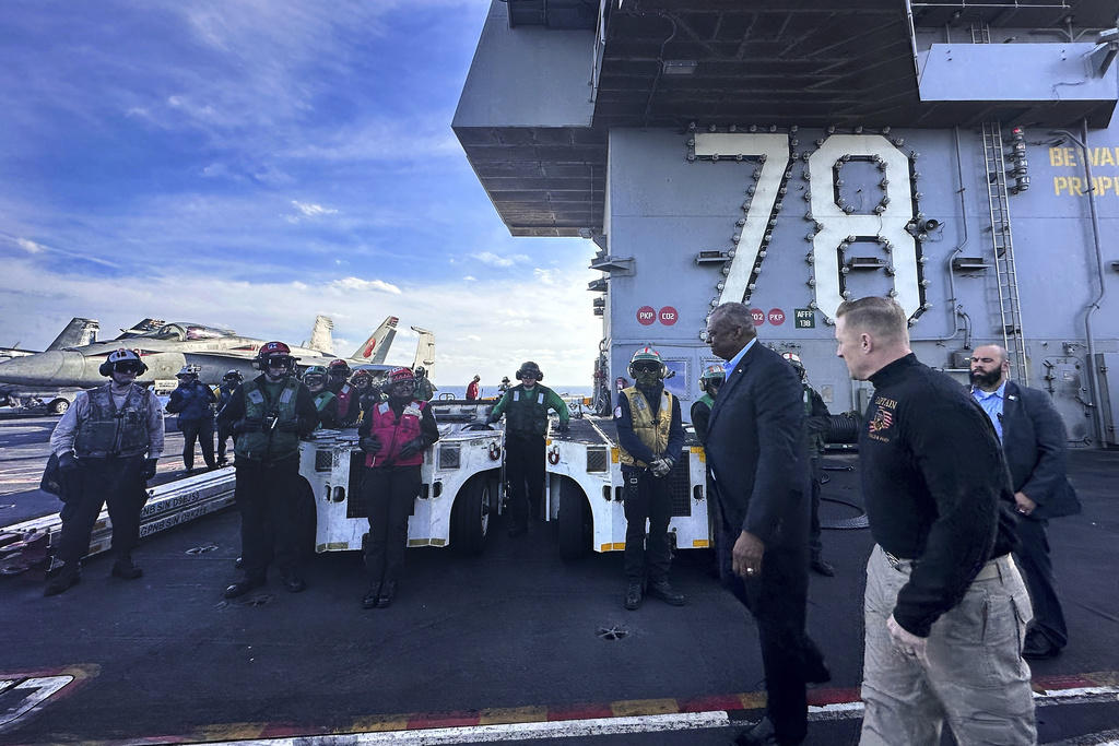 Defense Secretary Lloyd Austin, front left, walks next to the commanding officer of the USS Gerald R. Ford, Navy Capt. Rick Burgess