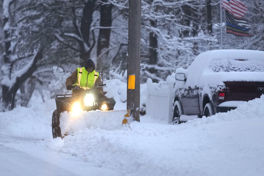 A man plows a snow covered driveway