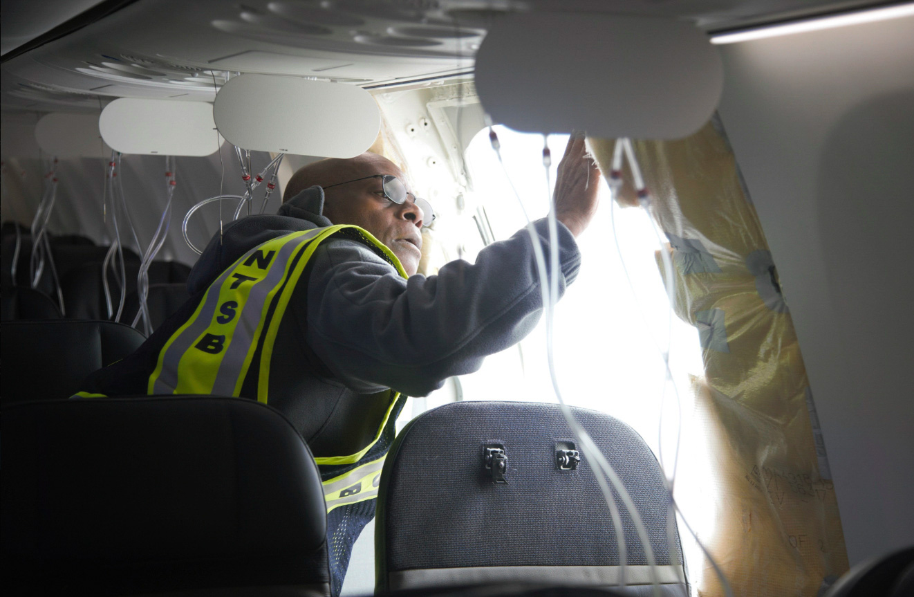 Agent inspects hole in side of plane