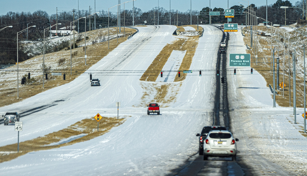 Motorists travel along an ice and snow covered Helton Drive in Florence, Ala.