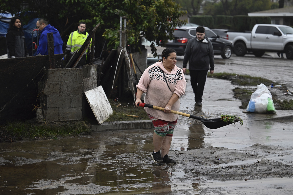 A woman removes debris from floods during a rain storm