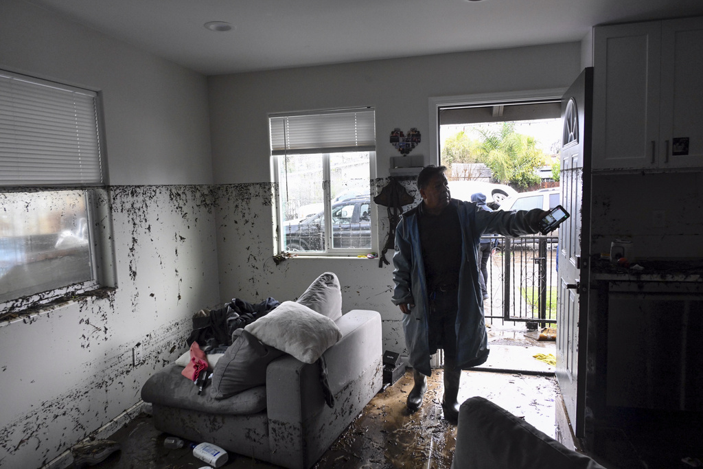 Man points to the water line inside his home that flooded during a rain storm