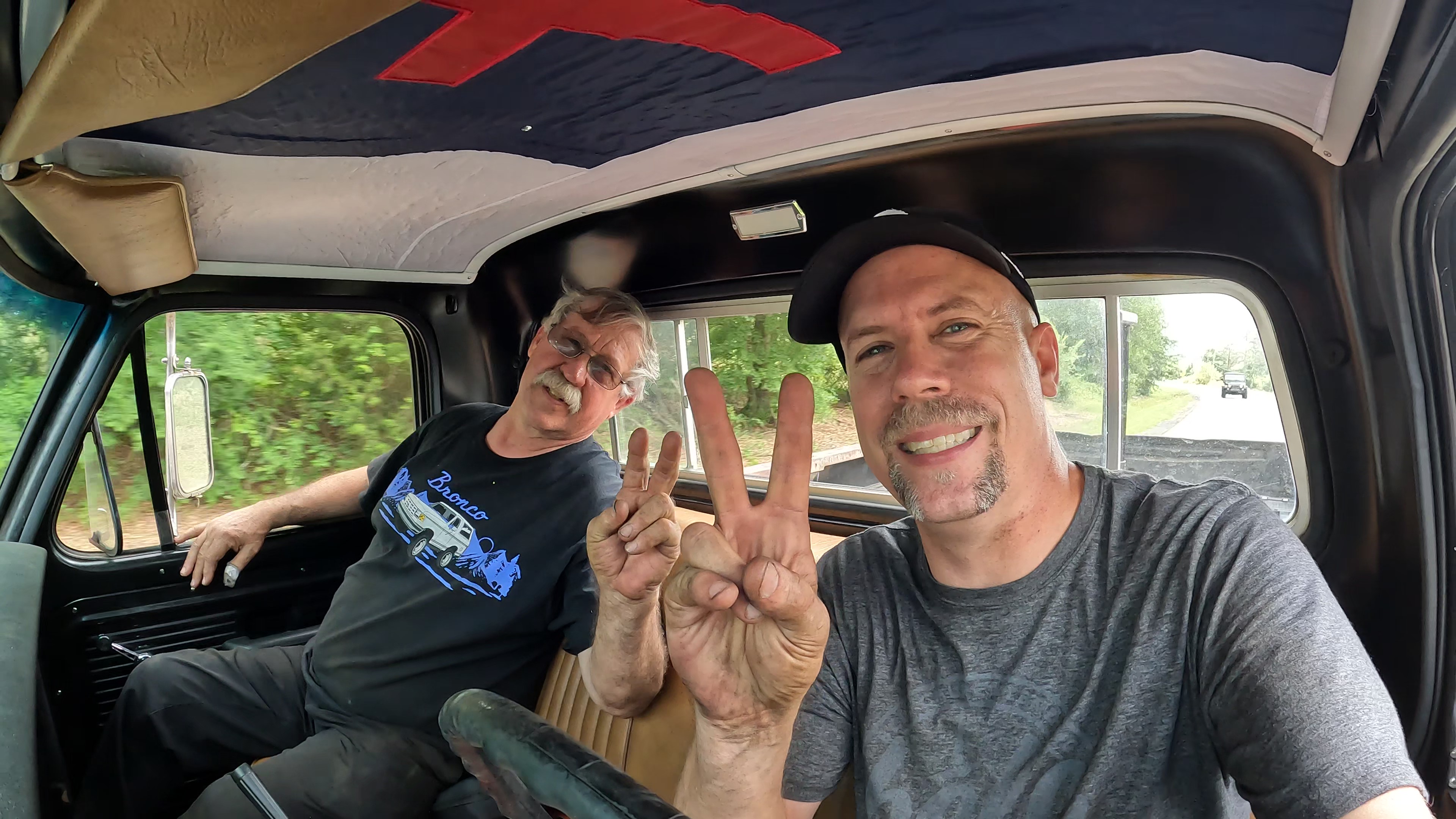 Pastor David Wheeler and his father sitting in vehicle cabin throwing peace signs