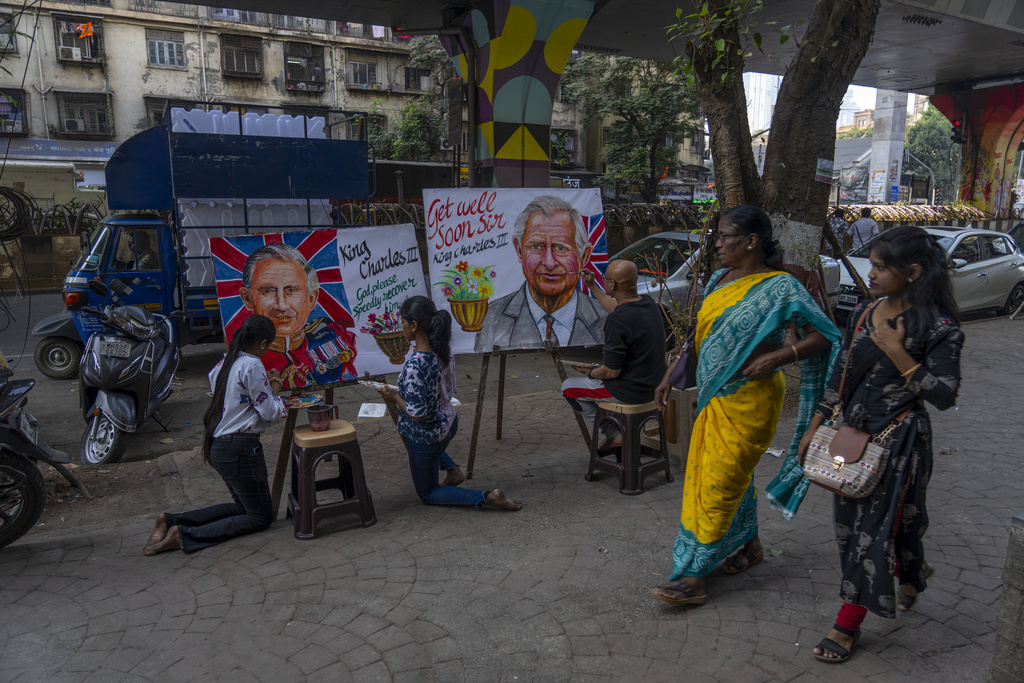 Pedestrians walk past as artists from Gurukul art school make paintings wishing Britain