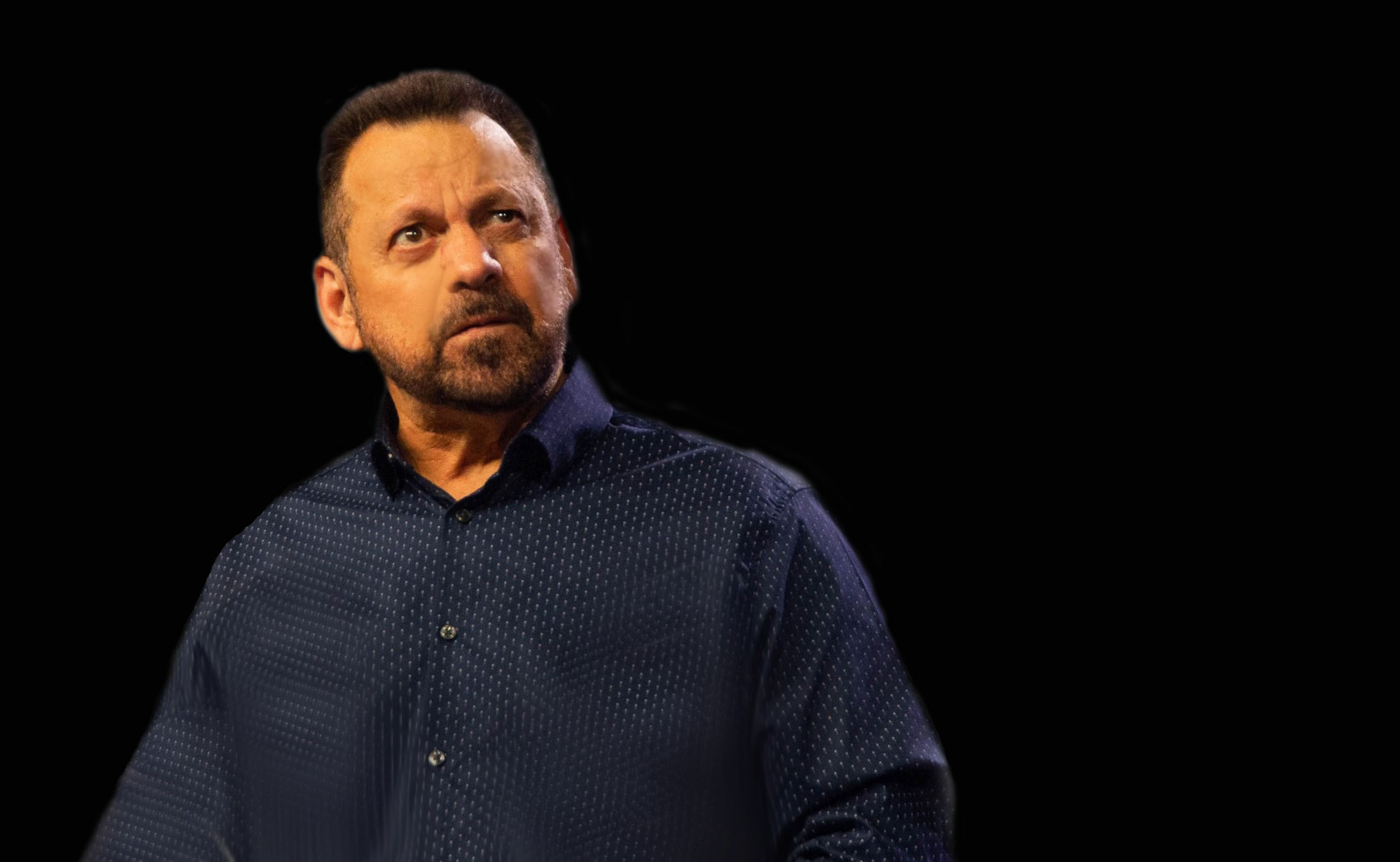Man in blue shirt with black background, goatee