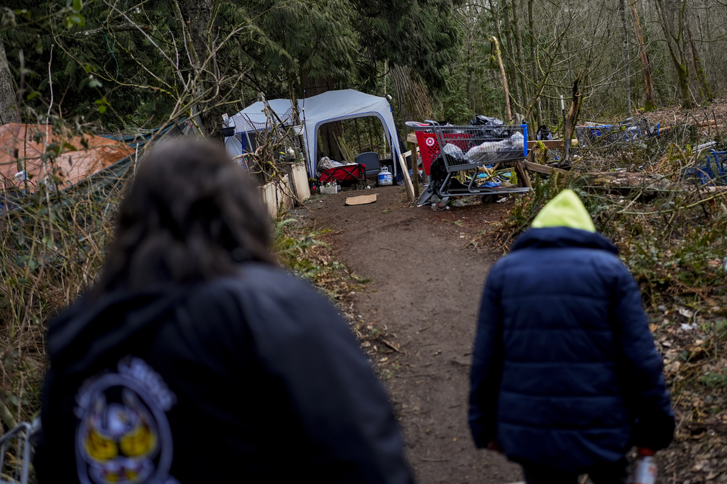 Rachel Cooper, 70, who says she was introduced to fentanyl by her kids, walks back to her tent with Lummi Nation crisis outreach supervisor Evelyn Jefferson, at left, at a longstanding homeless encampment near Walmart in Bellingham, Wash. 