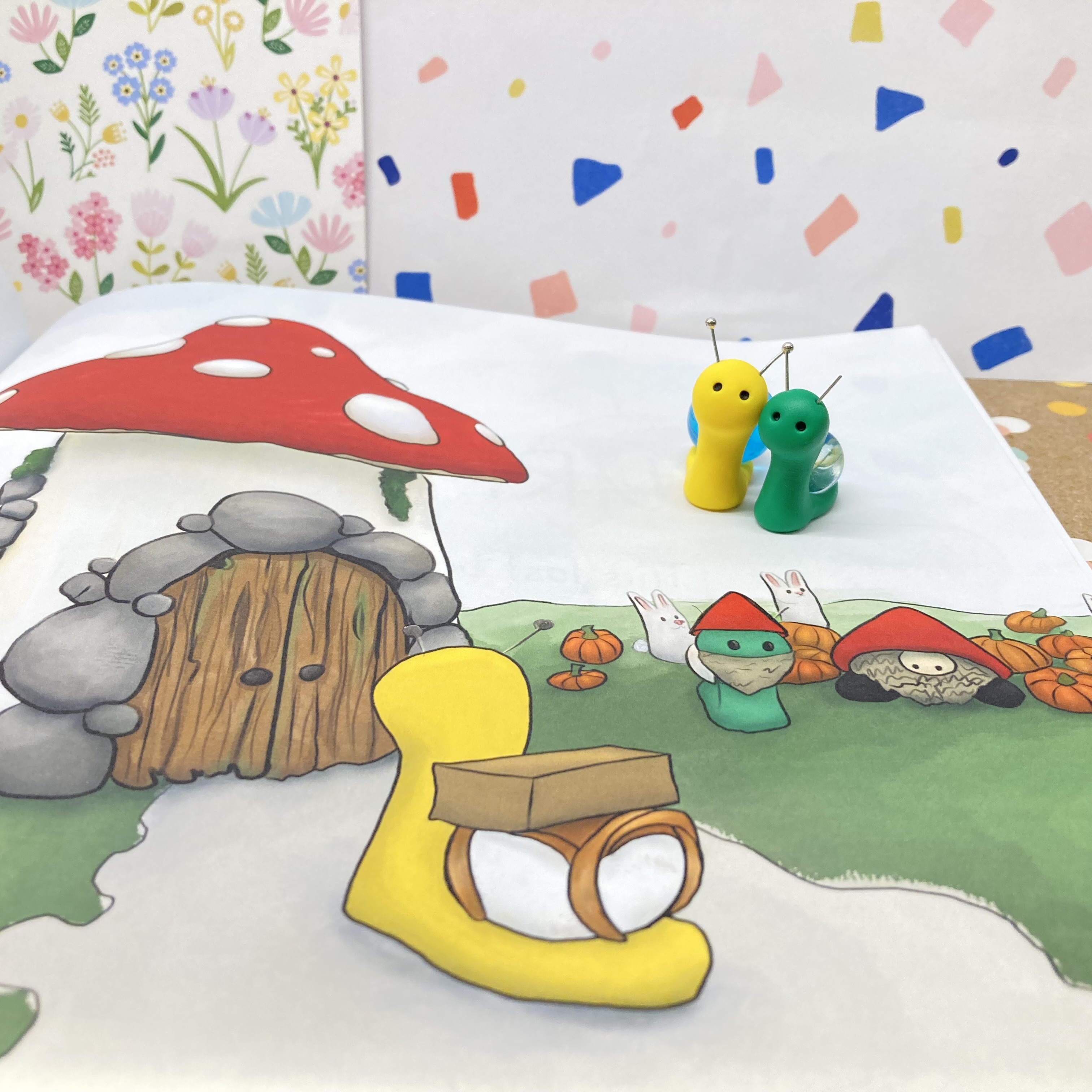 Clay snails Poppy (yellow) and Clover (green) sitting on a page of Eubank’s book