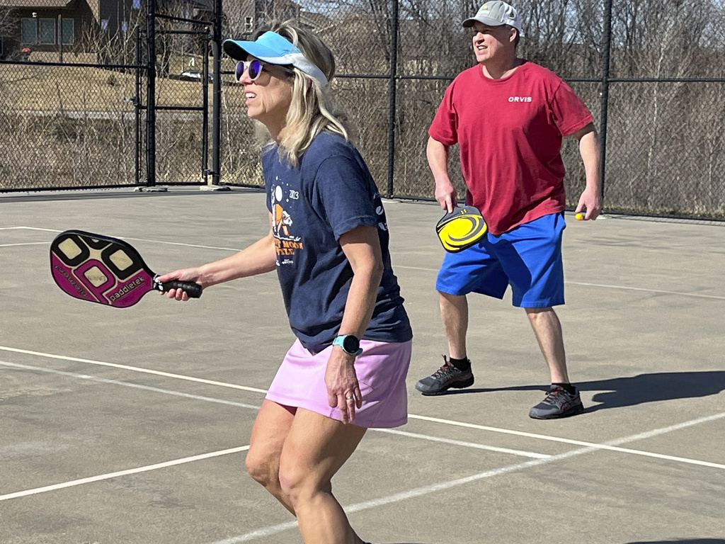 Stacy Lawson and her husband Hugh Lawson play a game of pickleball on an outdoor court in Omaha