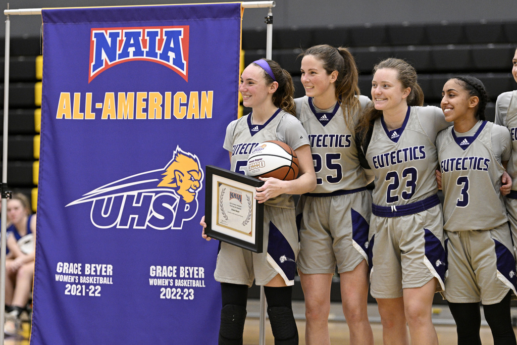 University Health Sciences and Pharmacy guard Grace Beyer holds a ball and plaque as her All-American achievement is honored following an NAIA college basketball game