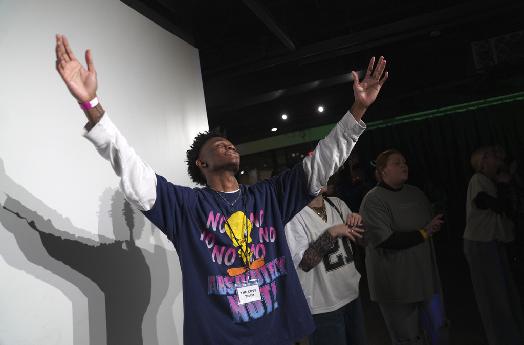 Jeremiah Manley, left, and other attendees at The Cove, an 18-and-up, pop-up Christian nightclub, raise their arms in worship