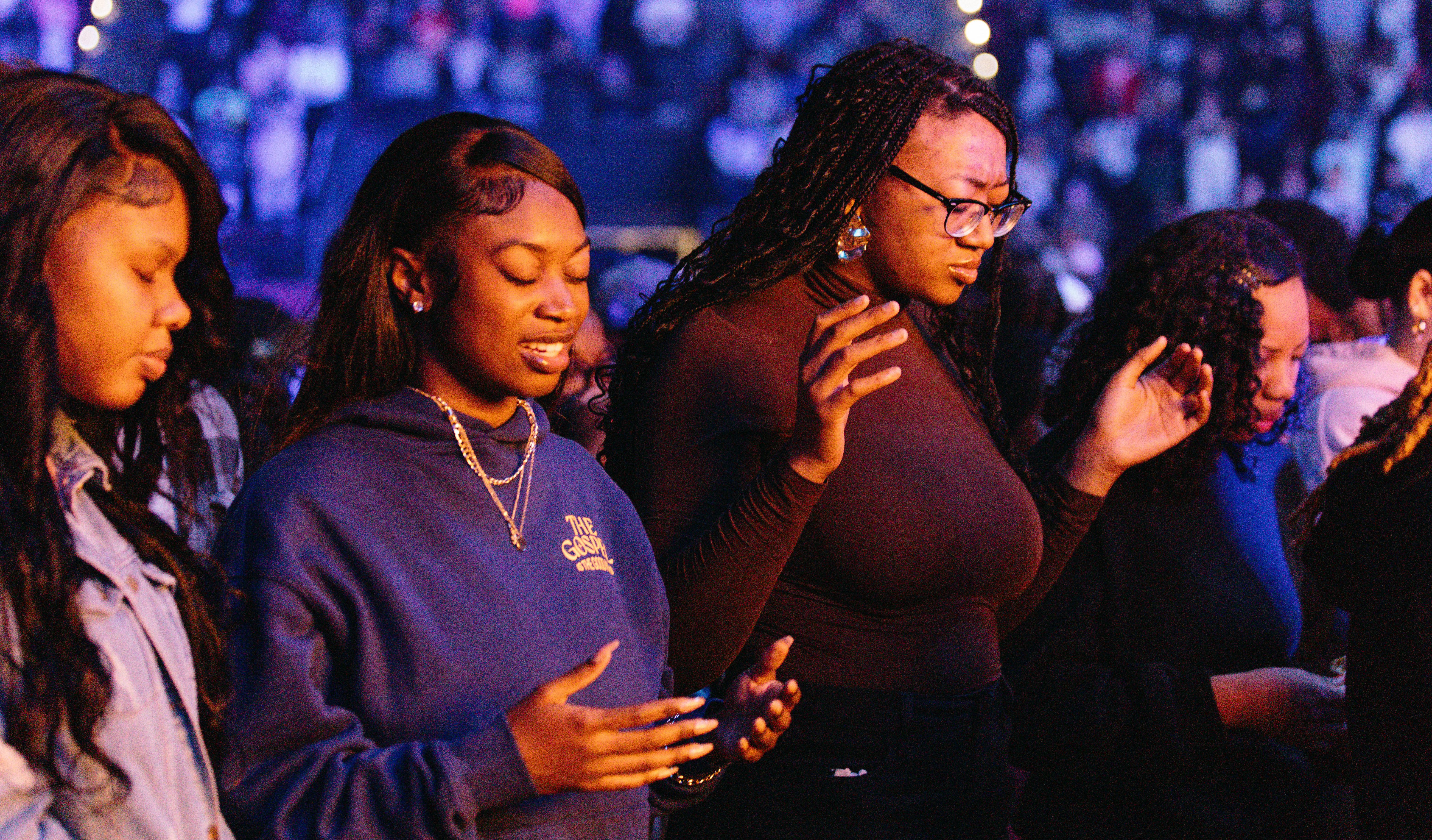 Four young women with their eyes closed, praying