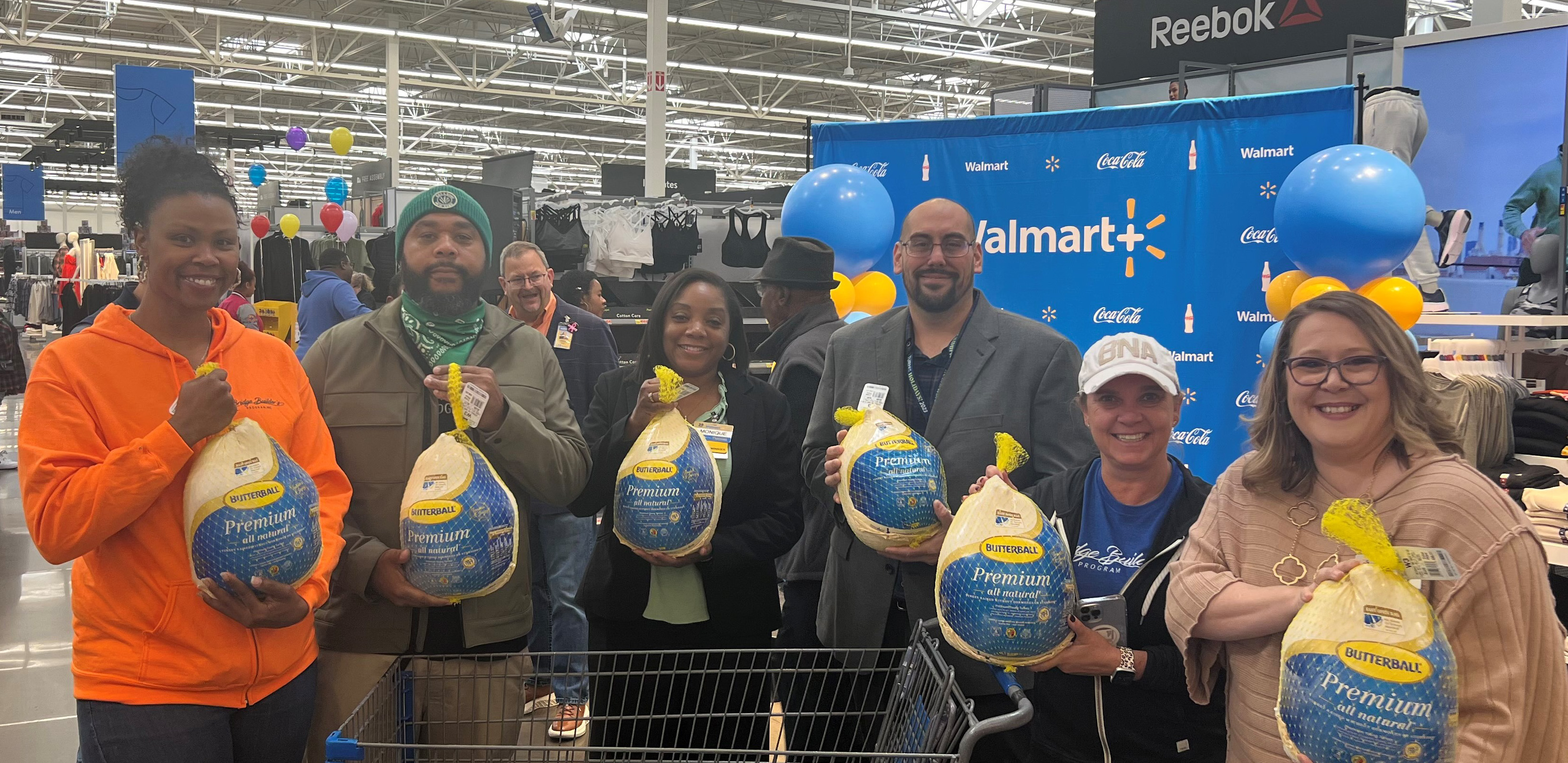 Six adults holding up frozen turkeys at Walmart