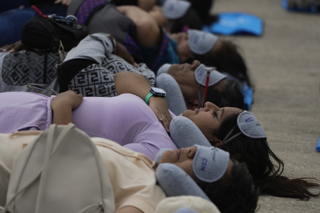 Equipped with mats, sleeping masks and travel pillows, people lie sprawled out 