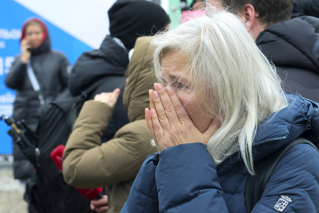 Woman reacts as she place flowers by the fence next to the Crocus City Hall, on the western edge of Moscow