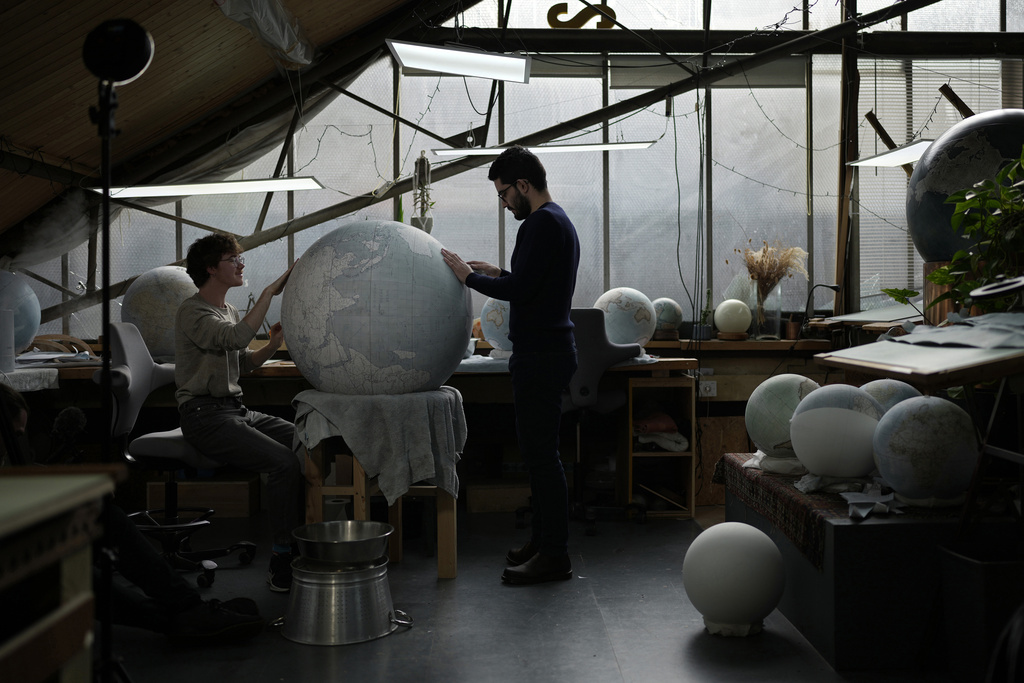 Artists make a globe at a studio in London