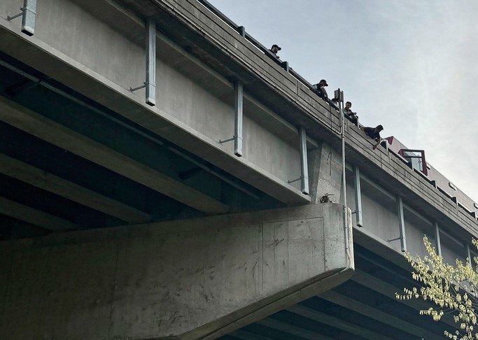 Chug perches on the support structure of a bridge high above the ground before he is rescued in Kansas City