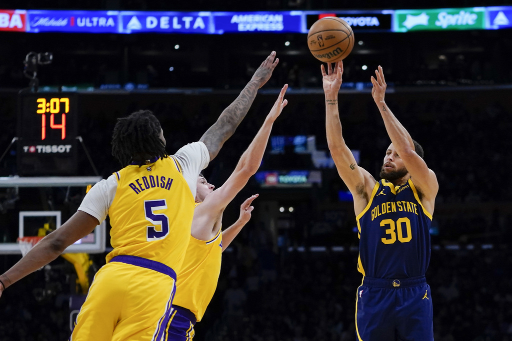 Golden State Warriors guard Stephen Curry, right, shoots against Los Angeles Lakers forward Cam Reddish, left, and guard Austin Reaves 