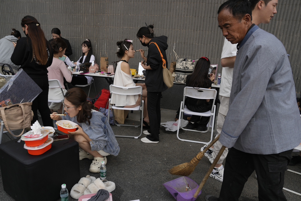 Models put on make up while others take a lunch break during Auto China 2024 in Beijing