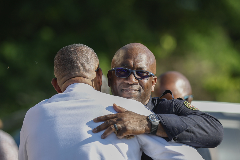 Charlotte fire department captain Brian Cunningham, right, hugs Charlotte-Mecklenburg Police Chief Johnny Jennings at a press conference