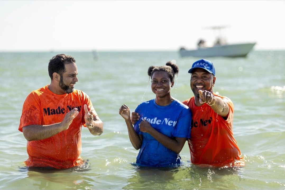 3 people standing in water at Tampa Bay baptism wearing shirts that say Made New