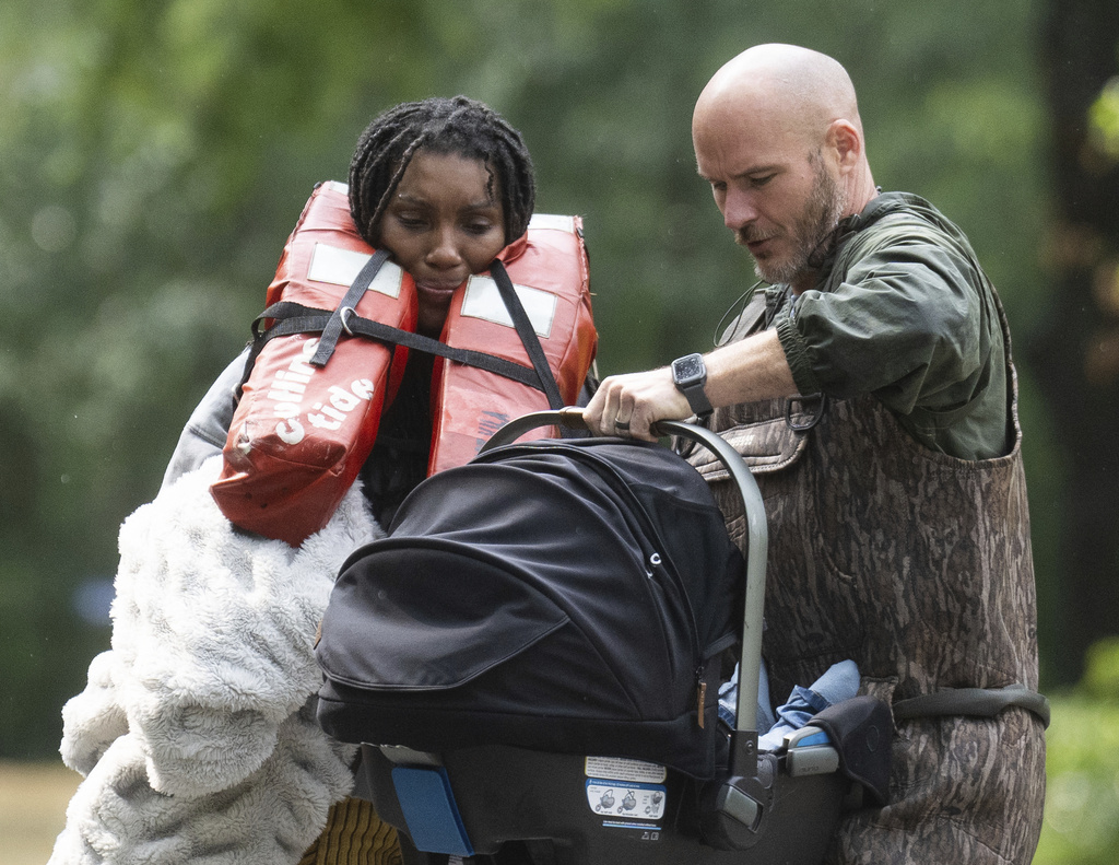A woman is handed her child after being evacuated by boat from her homes with the help of deputies with the Montgomery County Sheriff