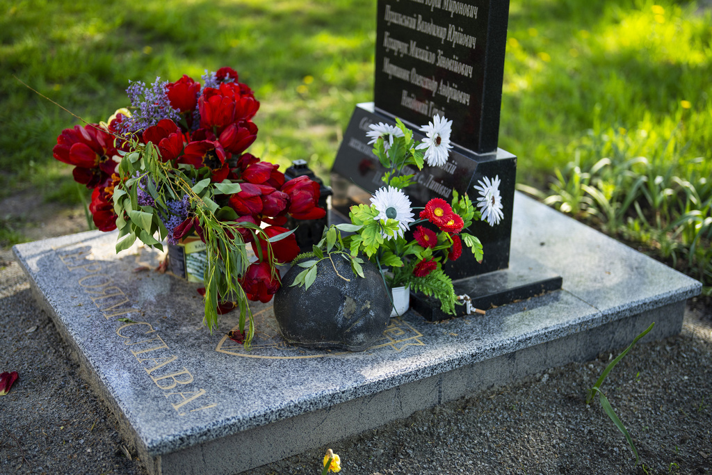 Flowers and a helmet rest at the memorial stone that commemorates the death of six Ukrainian soldiers killed by Russians, in the yard of the Church of the Intercession of the Blessed Virgin Mary in, Lypivka, near Lviv, Ukraine
