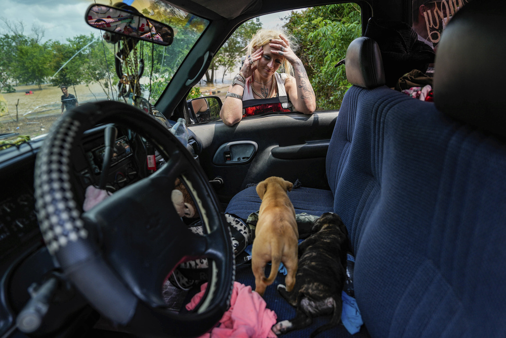A woman, who only gave her name as Lisamarie, checks on two of her puppies after her neighborhood was evacuated due to severe flooding