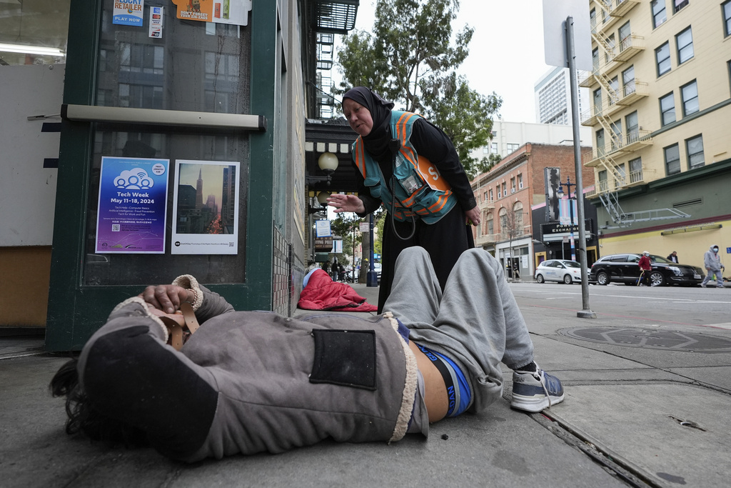 Tatiana Alabsi, right, checks on a man laying on a sidewalk and asks him to please move before children start walking to school in the Tenderloin neighborhood 