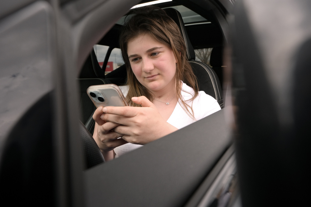 Alexis Bogan, whose speech was impaired by a brain tumor, uses an AI powered smartphone app to create a audible drink order at a Starbucks drive-thru on Monday, April 29, 2024, in Lincoln, R.I.