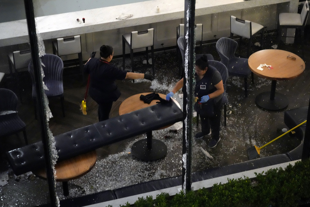 Workers clean up broken glass inside a damaged downtown Houston restaurant 