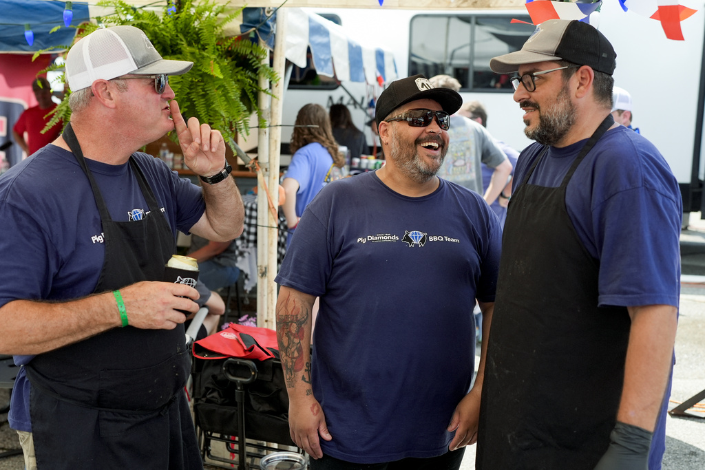 John Borden, left, Hugo Costa and Adriano Pedro, right, of the Pig Diamonds BBQ Team share a laugh at the World Championship Barbecue Cooking Contest