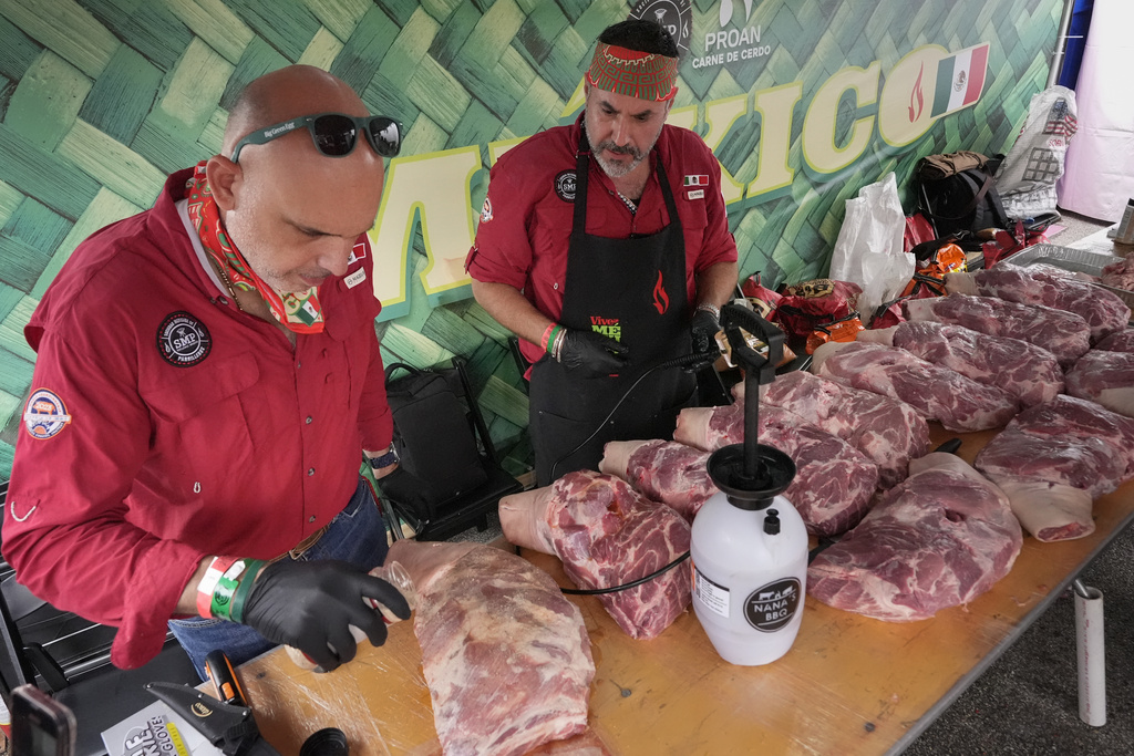 Juan Garza, left, and Mario Villarreal of the Sociedad Mexicano de Parrillieros team season pork shoulders at the World Championship Barbecue Cooking Contest