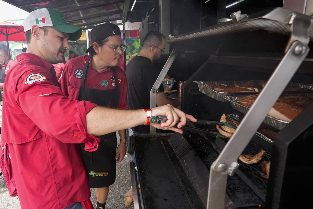Marcelo Trevino, left, and Arturo Gutierrez of the Sociedad Mexicano de Parrillieros team check food on the grill at the World Championship Barbecue Cooking Contest
