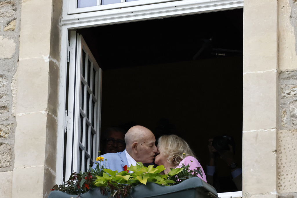 S WWII veteran Harold Terens, 100, left, and Jeanne Swerlin, 96, kiss from a window after celebrating their wedding at the town hall of Carentan-les-Marais, in Normandy, northwestern France, on Saturday