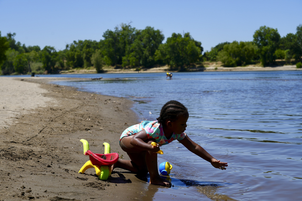 A young girl plays on the sand by the river in Sacramento, Calif.