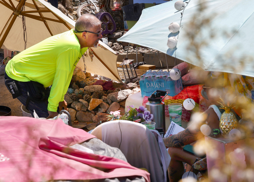 Louis Lacey, director of homeless response teams at Help of Southern Nevada, speaks to a homeless woman to offer water