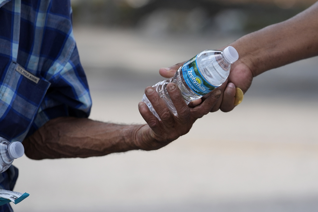 Ricky Leath, an outreach specialist with the City of Miami, right, hands a bottle of water to a person on the street as he works with the Miami-Dade County Homeless Trust 