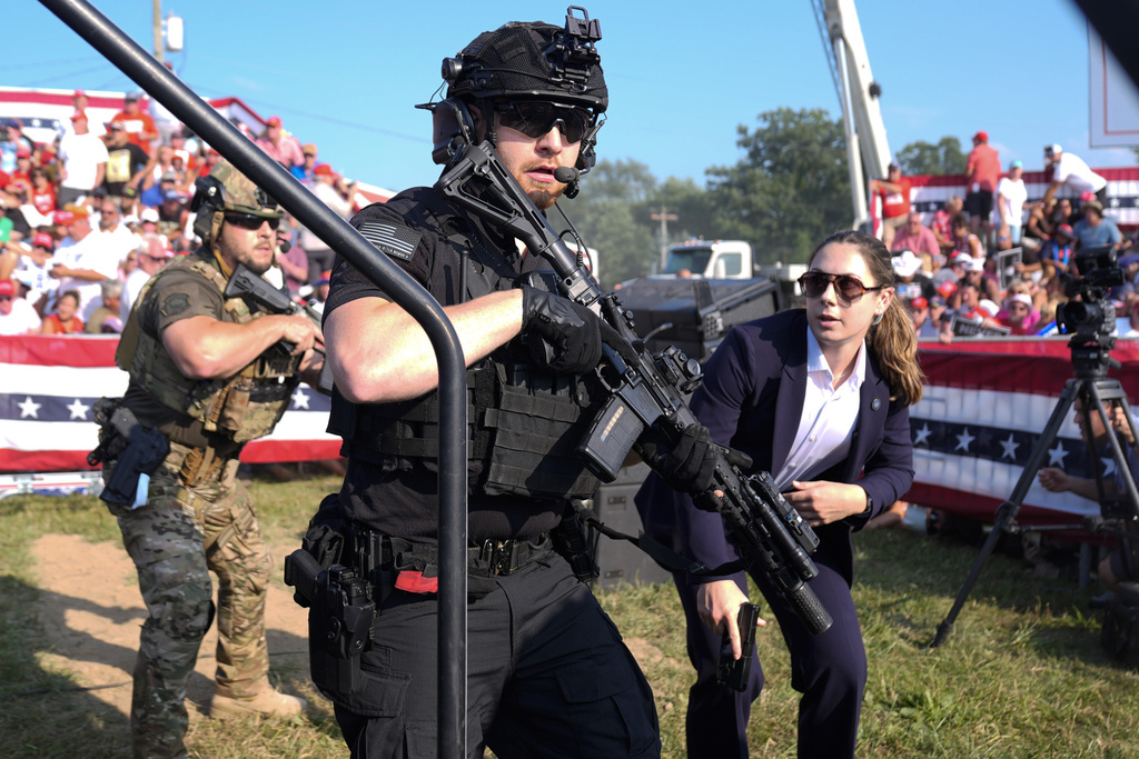 U.S. Secret Service agents respond as Republican presidential candidate former President Donald Trump is surrounded on stage by U.S. Secret Service agents at a campaign rally