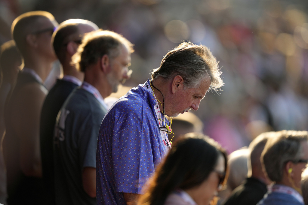 Fans bow their heads during a prayer for former President Donald Trump before an IndyCar auto race at Iowa Speedway in Newton, Iowa