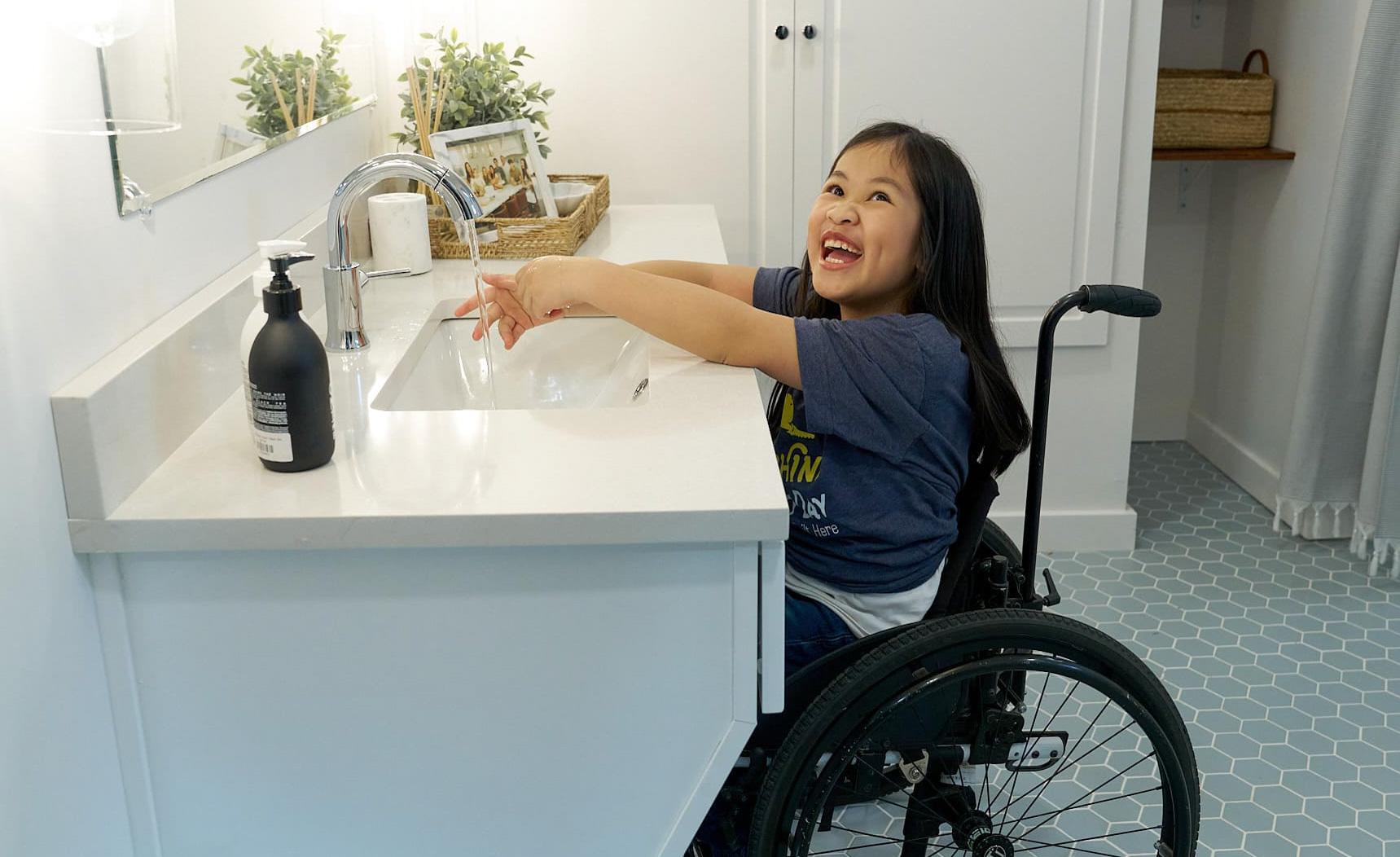 Little girl in a wheelchair-accessible bathroom, smiling