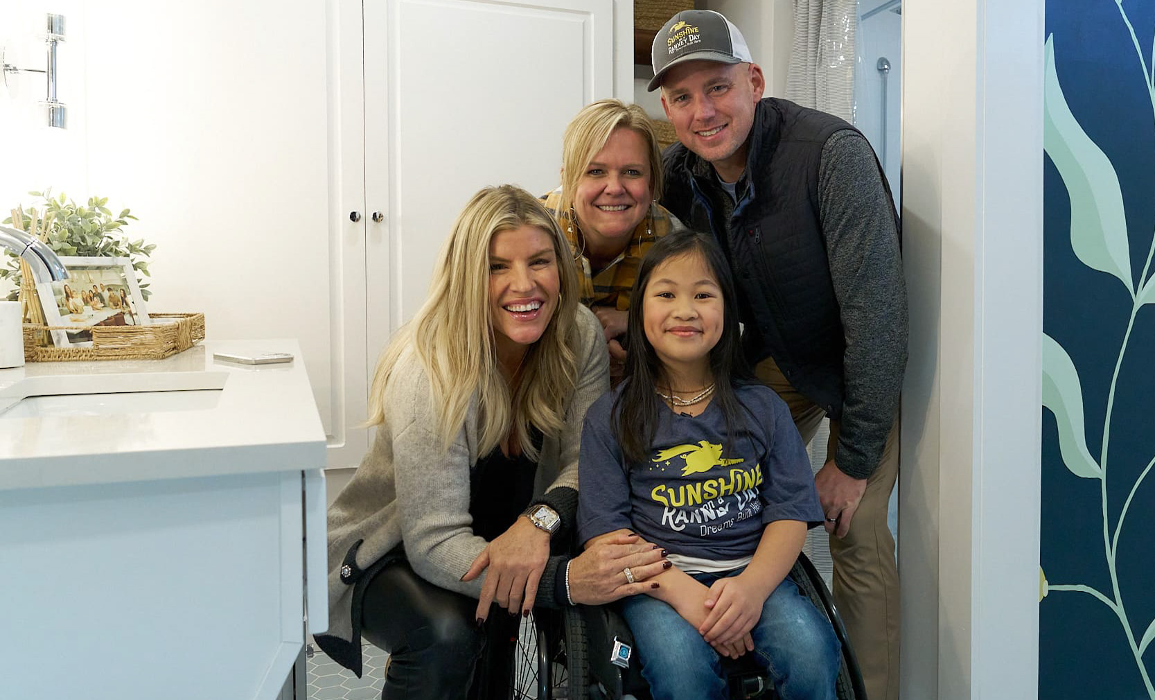 Three smiling adults, one child in a wheelchair