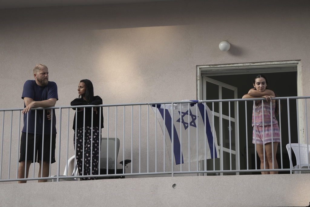 People watch from their balcony as Israeli police investigate the scene of a deadly explosion in Tel Aviv